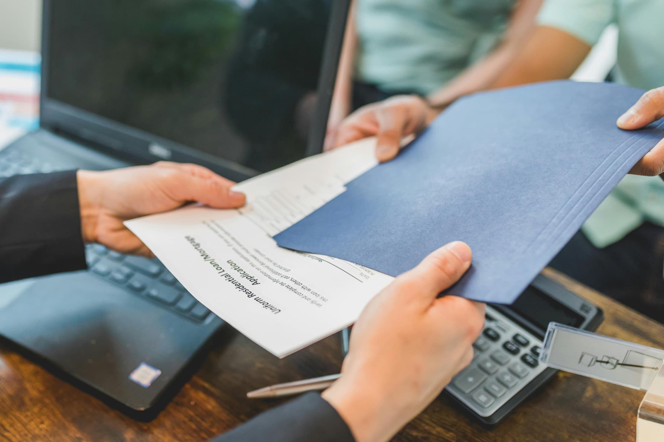 Mortgage loan documents being passed across a desk.