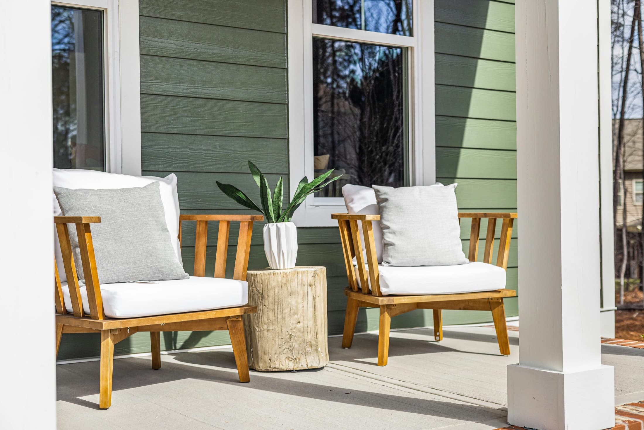 Covered front porch with two chairs outside a home.