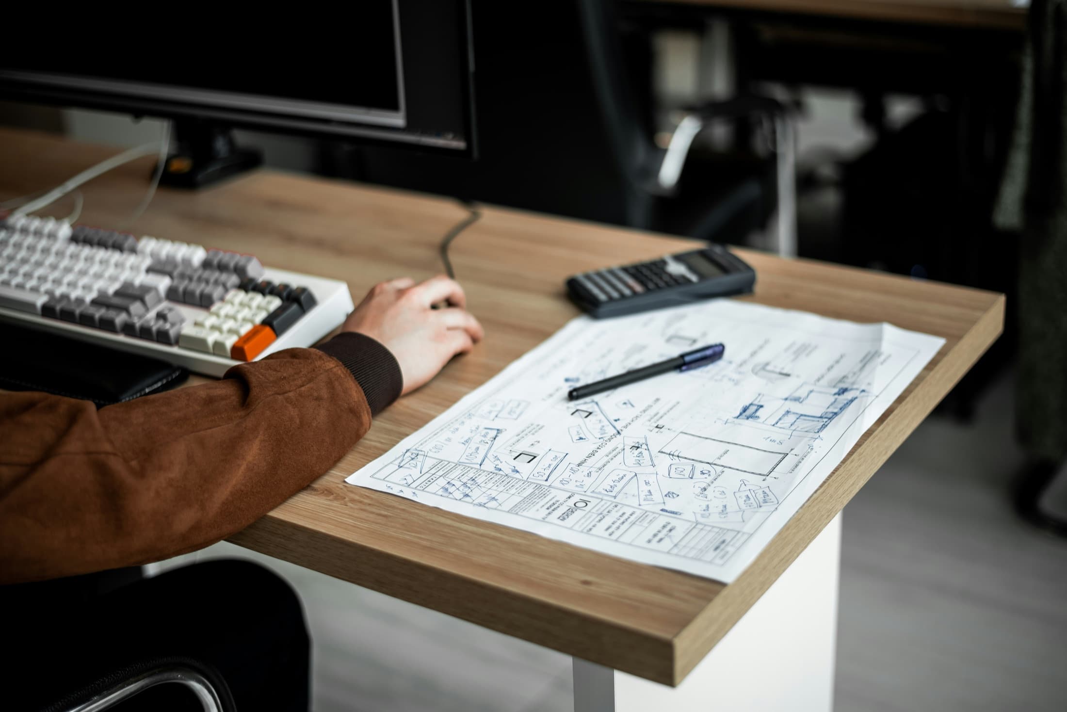 Marked-up construction plans on a desk beside a keyboard.